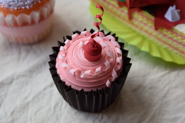 Un cupcake avec un glaçage rouge et rose, garni de mascarpone.