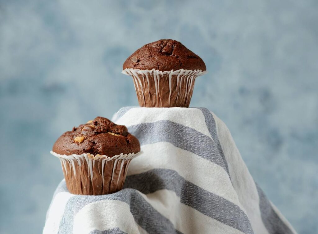 Deux muffins au chocolat sur un tissu bleu. 