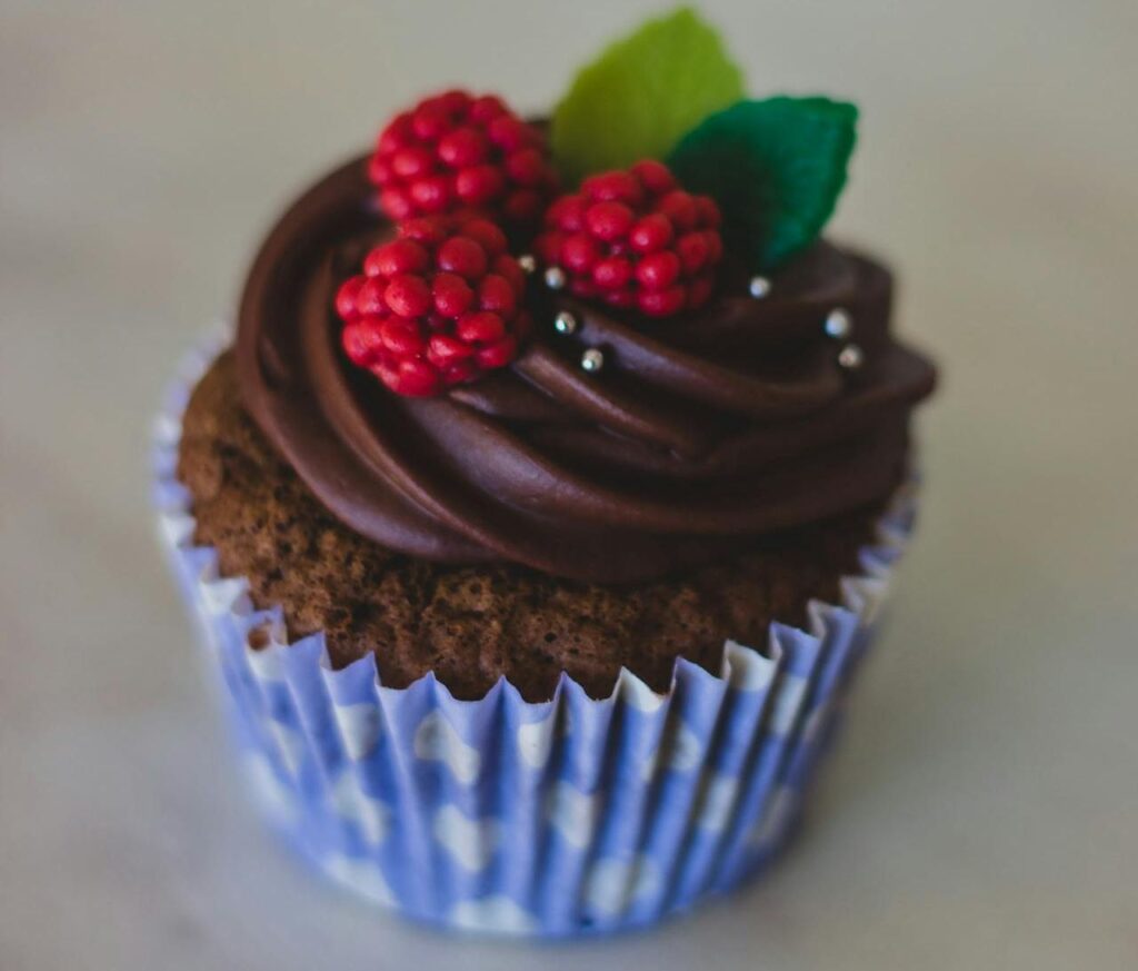 Un cupcake avec glaçage au chocolat et framboises